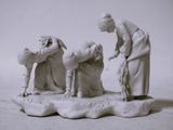 une figurine représentant une femme aidant un homme à mettre quelque chose dans l'eau