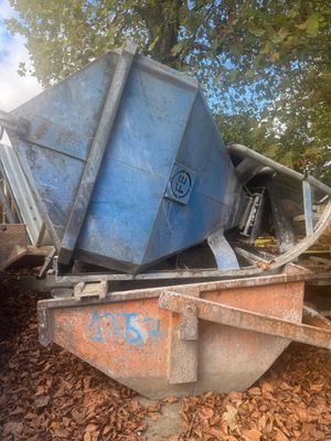une benne à ordures posée sur un tas de feuilles