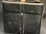 an old black briefcase with a brown strap on a black background
