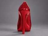 a close up of a red high heeled shoe on a gray surface