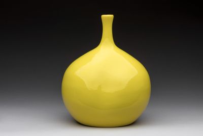 un vase jaune posé sur une table blanche
