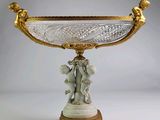 un vase doré et blanc surmonté d'une statuette