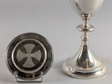 une coupe en argent posée à côté d'une assiette en argent sur une table