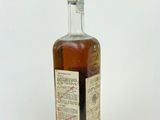an old bottle of whiskey sitting on top of a white surface