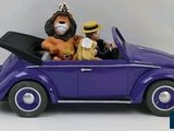 toy figurines of two people in a purple car with a lion on the roof
