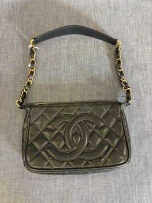 un petit sac Chanel noir avec une bandoulière en chaîne dorée