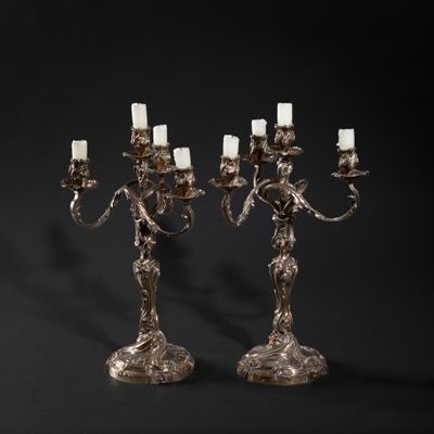 a pair of silver plated candelabs with candles