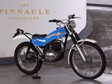 une moto bleue et blanche garée devant l'enseigne « Pinnacle Collection »