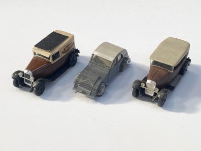 trois petites voitures assises l'une à côté de l'autre sur une surface blanche