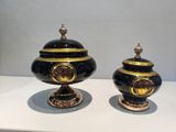 two black and gold vases sitting on a white table