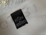 the label of a white dress with silver sequins on it
