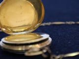 a gold pocket watch sitting on a black cloth