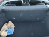 the trunk of a red car with a bag of groceries in it