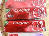 two tubes of colgate toothpaste sitting on a tray next to a cup of coffee