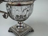 an antique silver plated teapot with a lid and a spoon on a stand