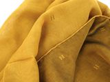 mustard colored scarf with the letter h on it laying on top of a white surface