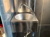 a stainless steel sink in the corner of a bathroom