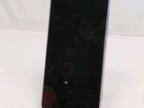 a black cell phone sitting on a stand on a white surface