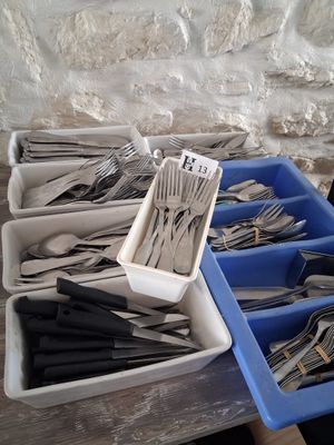several trays of forks and spoons sitting on top of a wooden table
