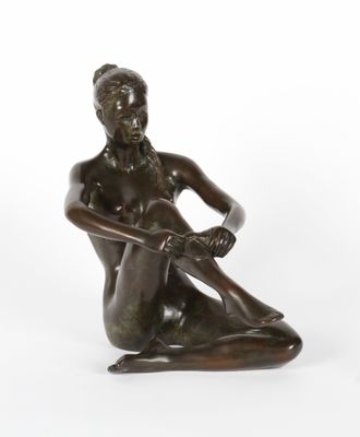 une statue en bronze représentant une femme assise par terre