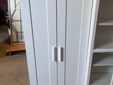 a white cabinet with a door and shelves in the room