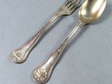 two silver spoons and a fork sitting on a table