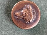 un badge en métal sur lequel est représenté un chien