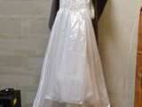 a white dress hanging on a clothes rack in a room