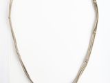 un collier en argent composé de trois brins de fil d'argent sur fond blanc