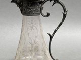 a glass pitcher with a metal handle on a table