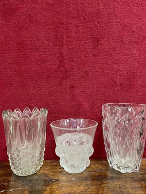 trois vases en verre posés sur une table en bois, près d'un mur rouge