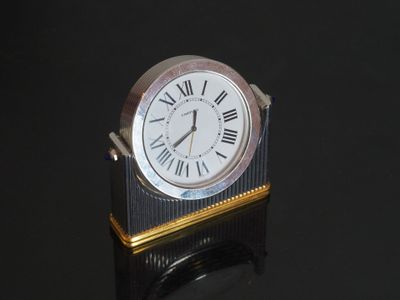une horloge argentée avec des chiffres romains, posée sur un support noir