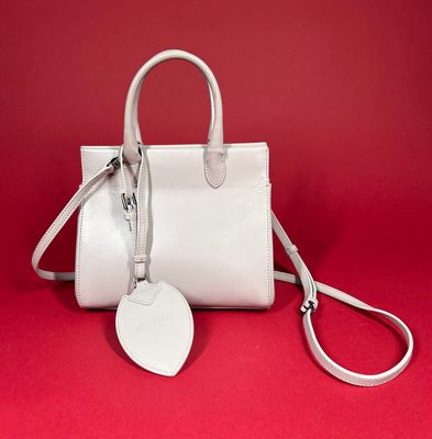 a white purse with a tag on it on a red background