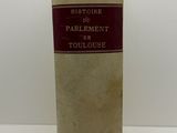 un vieux livre posé sur une table à côté d'un mur blanc