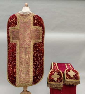un tissu rouge et doré orné d'une croix, à côté d'une boîte rouge