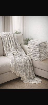 towels stacked on a couch in a living room next to a window