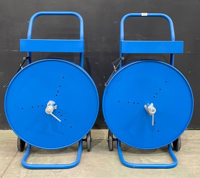 deux bobines en acier bleu posées sur des roulettes, adossées à un mur noir
