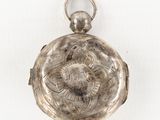 an antique silver pocket watch on a white surface with a white background