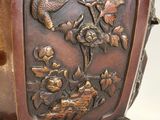 a brown vase with a bird and flowers on it