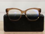 glasses are sitting on a black case on a wooden table