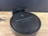 un aspirateur robot noir posé sur une table en bois