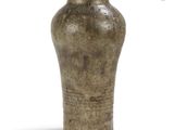un vase brun posé sur une surface blanche