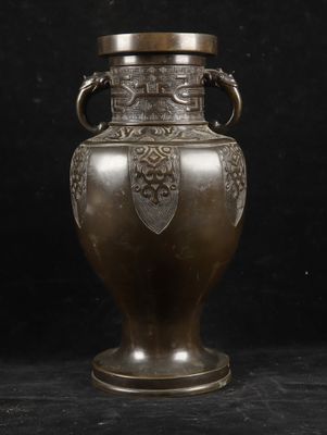 an antique bronze vase with handles on a black background