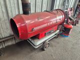 un chauffage au gaz rouge posé sur un chariot devant un immeuble