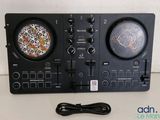 un gros plan d'un contrôleur de DJ posé sur une table à côté d'un chargeur
