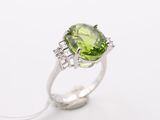 a close up of a ring with a green stone and diamonds