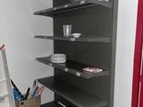 a shelf in the corner of a room with many items on it