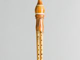 someone is holding a wooden flute in their hand on a gray background