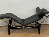 une chaise longue en cuir noir posée sur un parquet