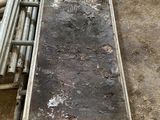 a long piece of metal on the ground next to a pile of pipes